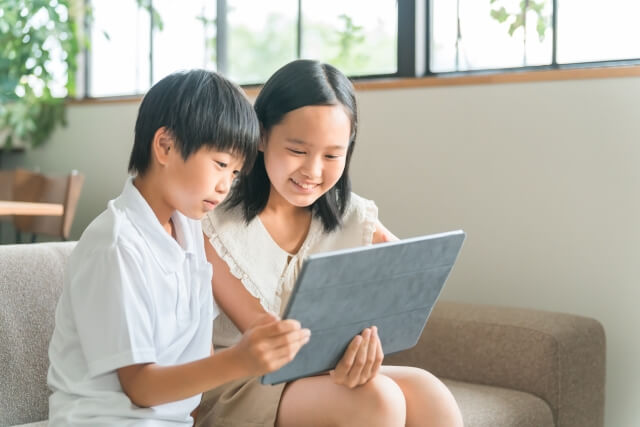 ソファでタブレットを見る親子の様子